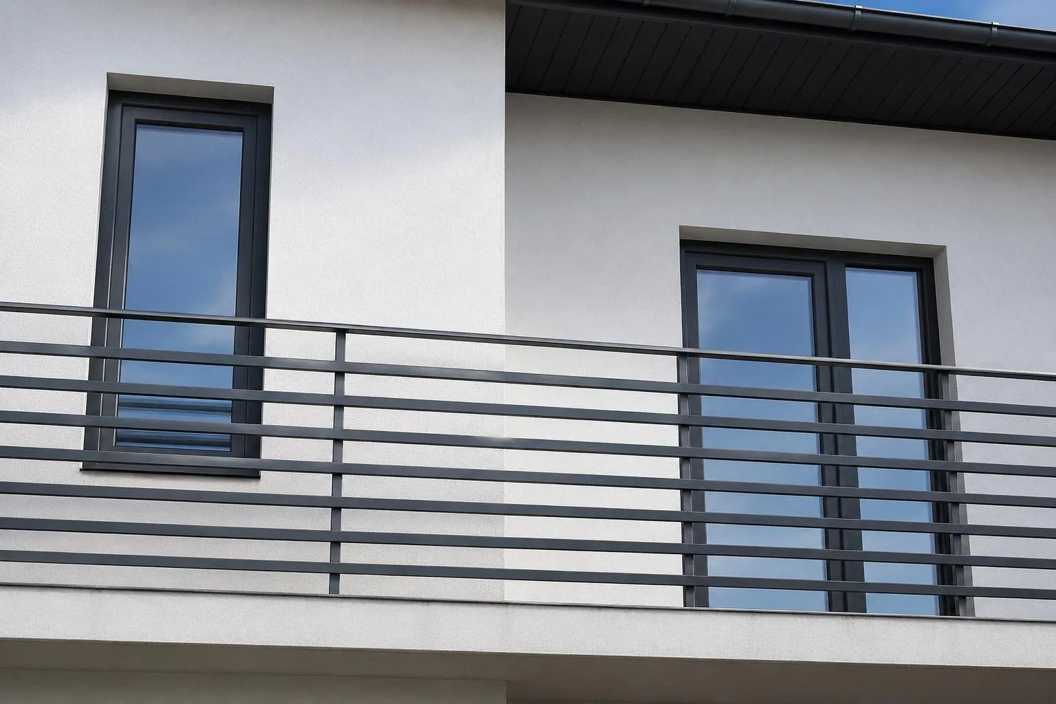 Finestre antracite su una facciata bianca con balcone