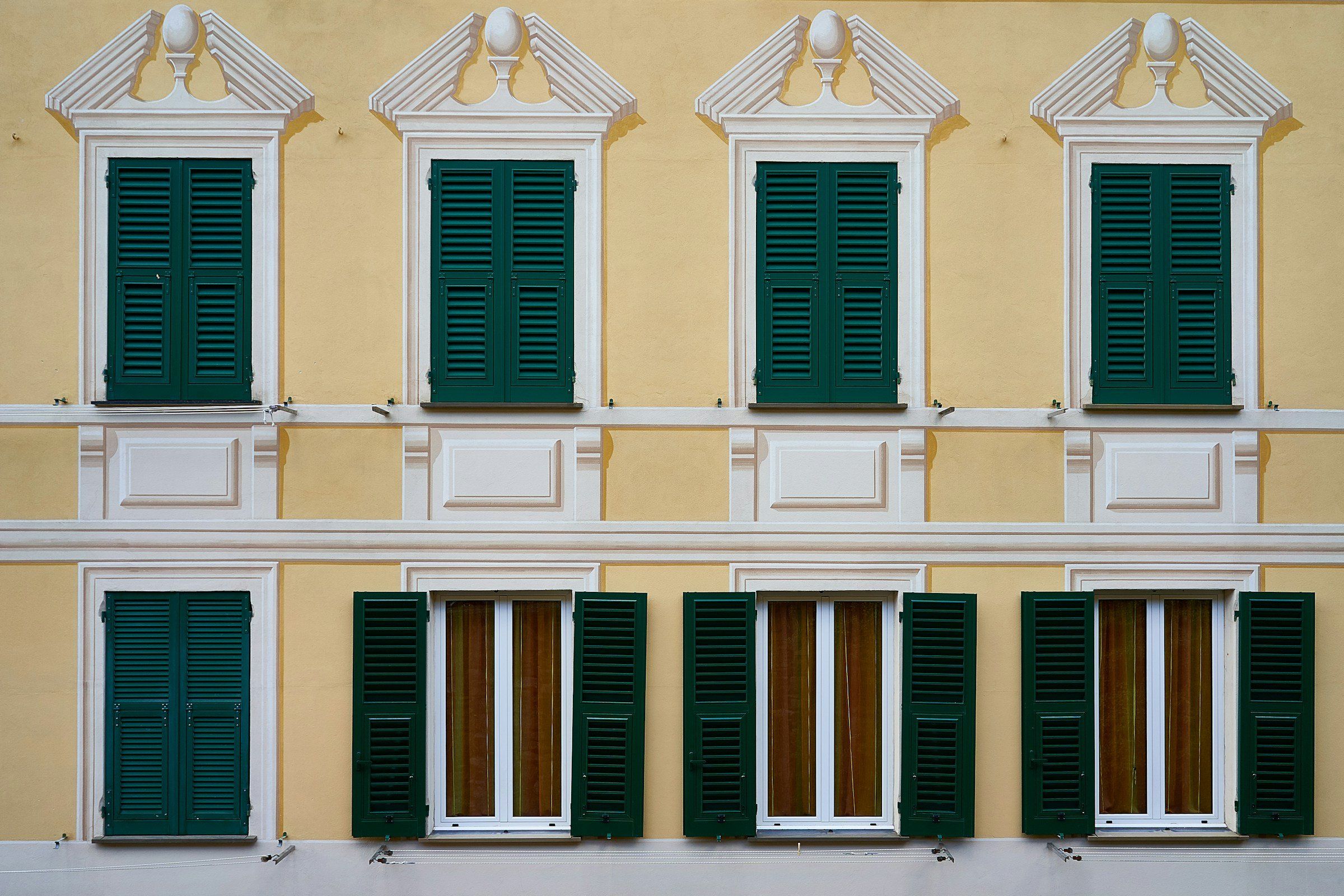 Scuri verdi su una facciata gialla di un palazzo italiano